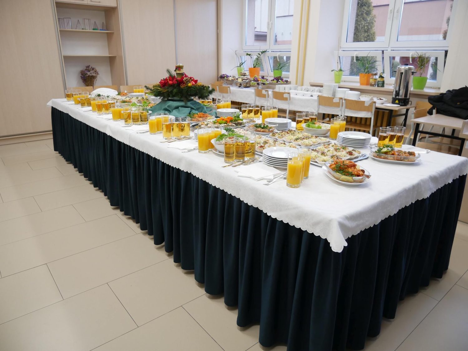Długi stół cateringowy z przekąskami, sałatkami i napojami, przygotowany przez Restaurację Kargul