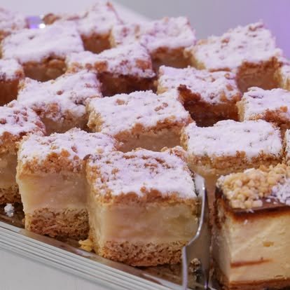Porcje jabłecznika z lukrem i sernika z kruszonką ułożone na tacy, obok łopatka do ciasta